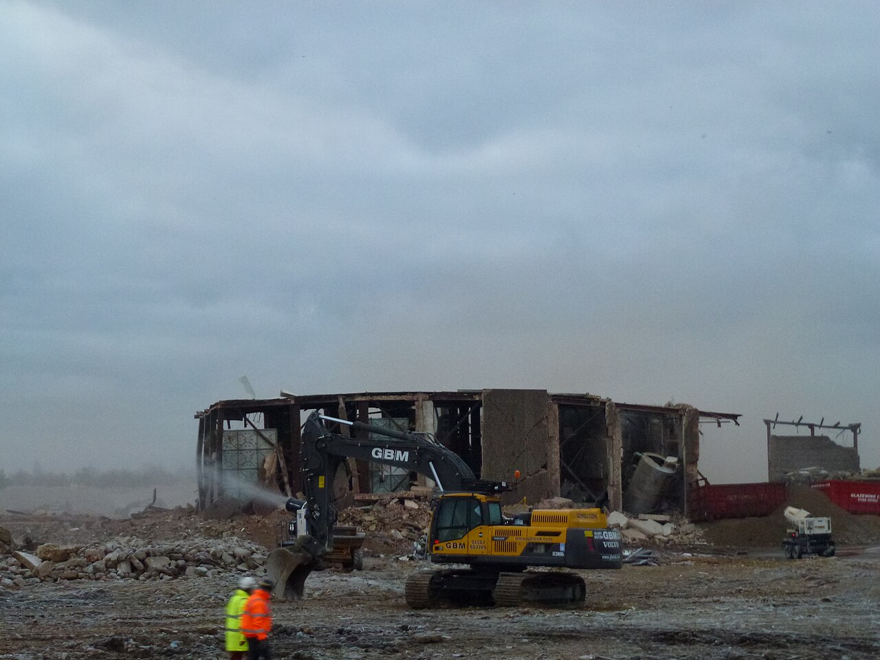 Demolition site raising dust, with water spray suppression